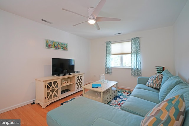 living area featuring a ceiling fan, light wood-style flooring, and baseboards