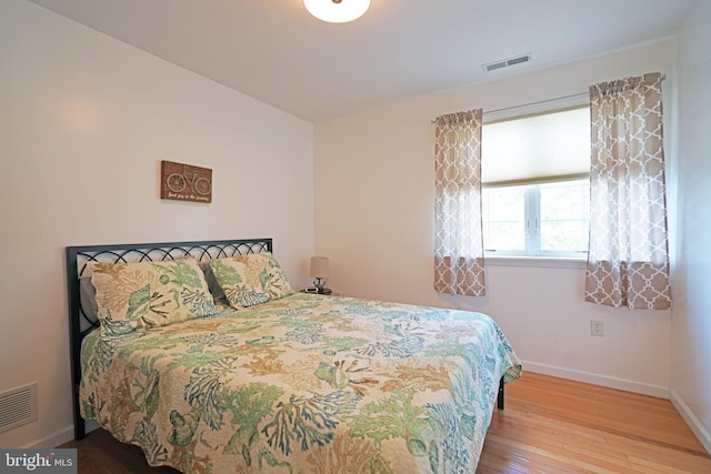 bedroom with wood-type flooring and baseboards
