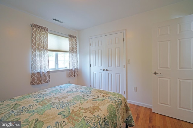 bedroom with light wood-style floors, a closet, and baseboards