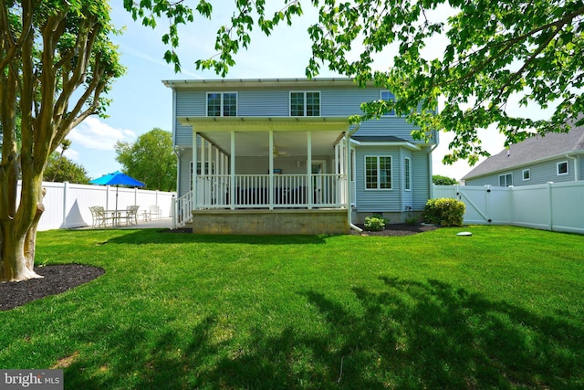 back of property with a sunroom, a gate, and a patio area