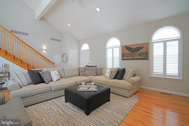 living room featuring beam ceiling, wood finished floors, stairs, high vaulted ceiling, and baseboards