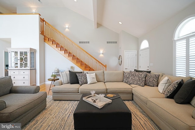 living area with high vaulted ceiling, stairs, and wood finished floors