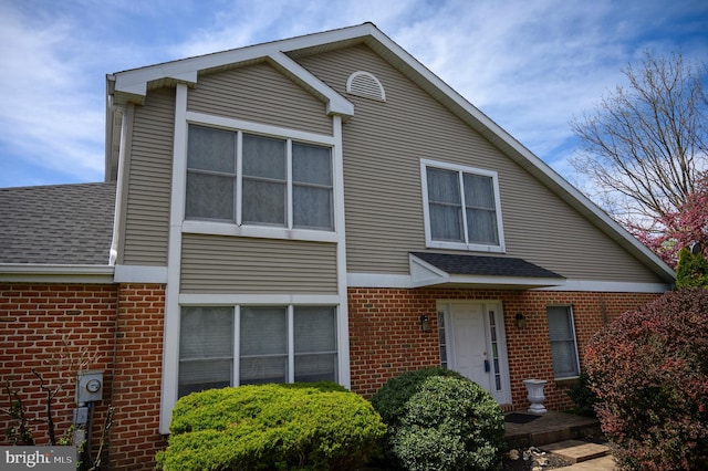 view of front of property with brick siding and a shingled roof