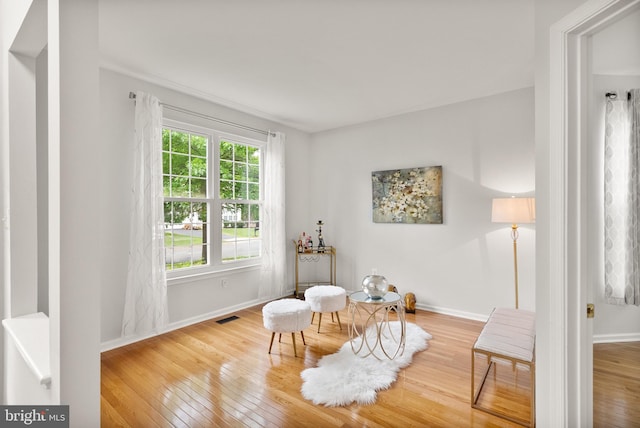 living area with hardwood / wood-style flooring, baseboards, and visible vents