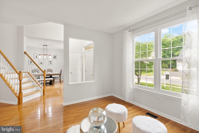 living area with a notable chandelier, stairway, baseboards, visible vents, and light wood-style floors