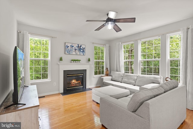 living room with a ceiling fan, a wealth of natural light, and light wood-style flooring