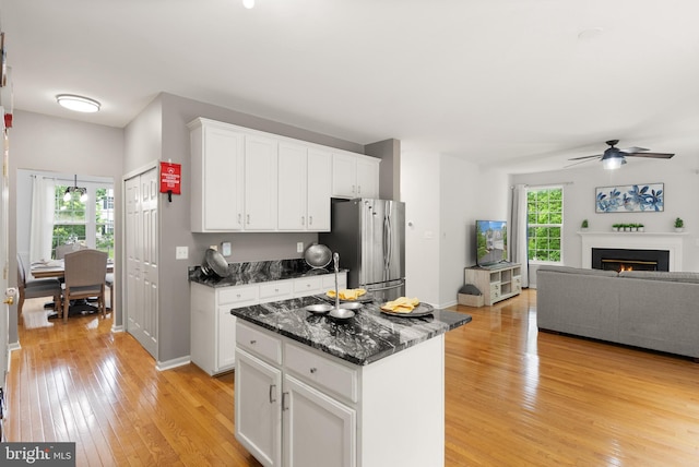 kitchen with freestanding refrigerator, light wood finished floors, open floor plan, a ceiling fan, and white cabinets