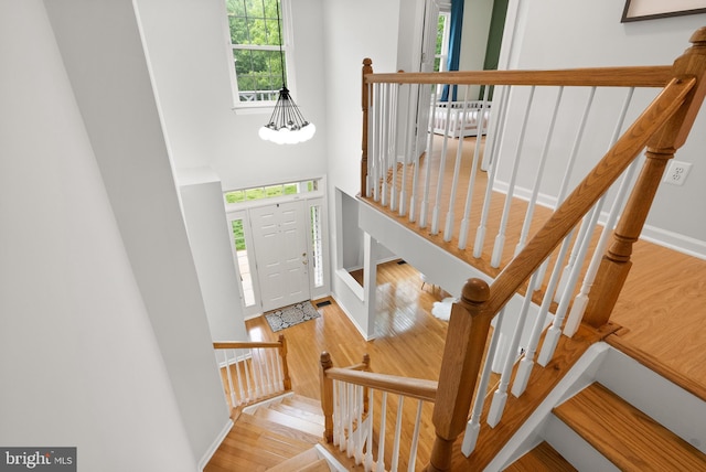 foyer with stairway, a high ceiling, baseboards, and wood finished floors