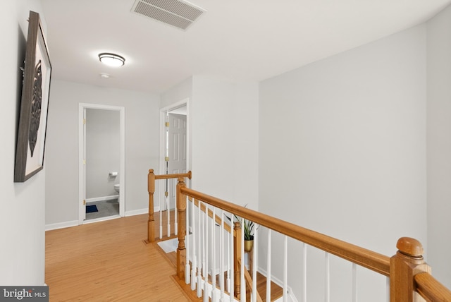 corridor featuring light wood-style flooring, baseboards, an upstairs landing, and visible vents