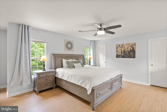 bedroom featuring baseboards, light wood-type flooring, and multiple windows