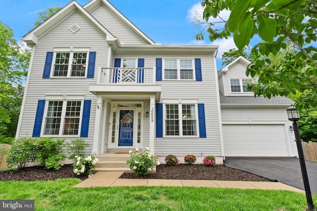 view of front facade featuring aphalt driveway, a garage, and a balcony