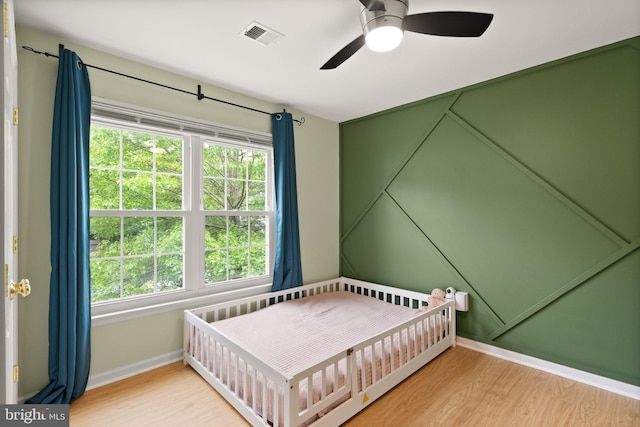 bedroom featuring baseboards, a ceiling fan, visible vents, and wood finished floors