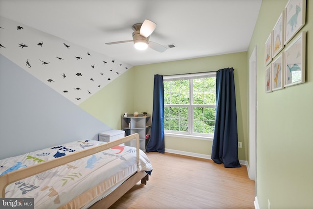 bedroom with light wood finished floors, visible vents, baseboards, ceiling fan, and lofted ceiling