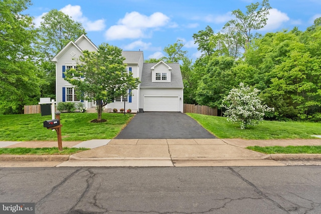 view of front of property featuring aphalt driveway, fence, an attached garage, and a front lawn