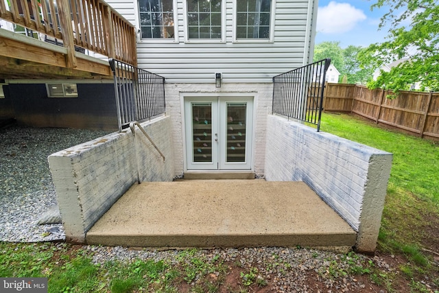 property entrance featuring a yard, fence, french doors, and brick siding