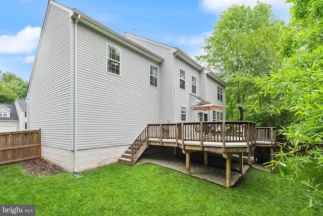 back of property featuring a yard, a wooden deck, and fence