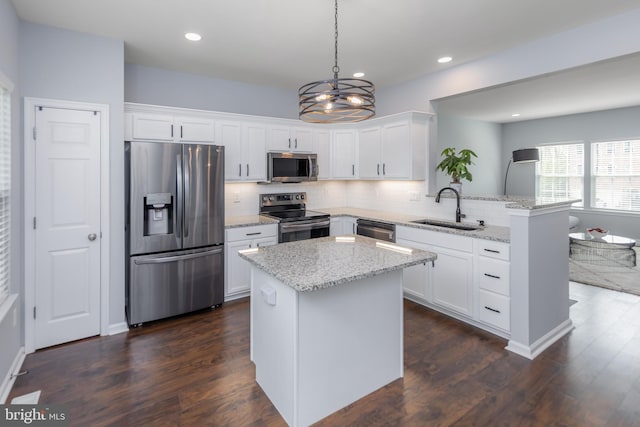 kitchen featuring tasteful backsplash, a sink, stainless steel appliances, white cabinets, and a peninsula