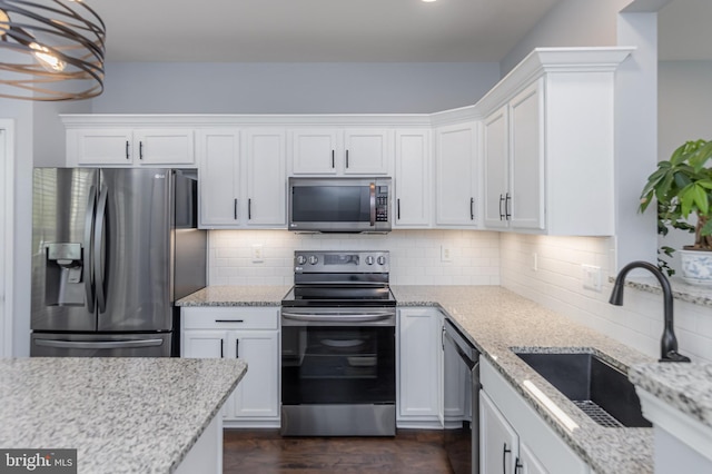 kitchen with appliances with stainless steel finishes, tasteful backsplash, a sink, and white cabinetry
