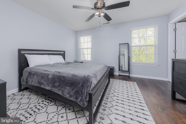 bedroom with wood finished floors, visible vents, a ceiling fan, and baseboards