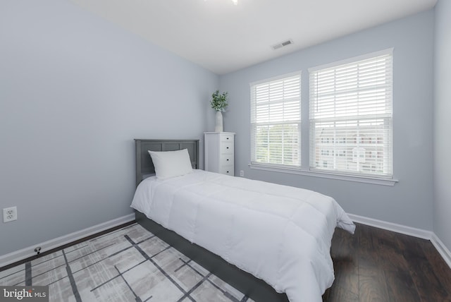 bedroom with baseboards, wood finished floors, and visible vents