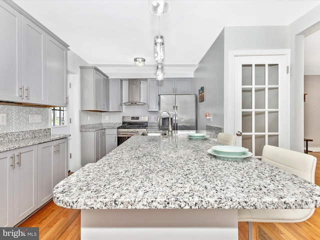 507 Kerwin Ct, Silver Spring, MD 20901 - kitchen with stainless steel appliances, wall chimney range hood, a sink, gray cabinets, and a breakfast bar