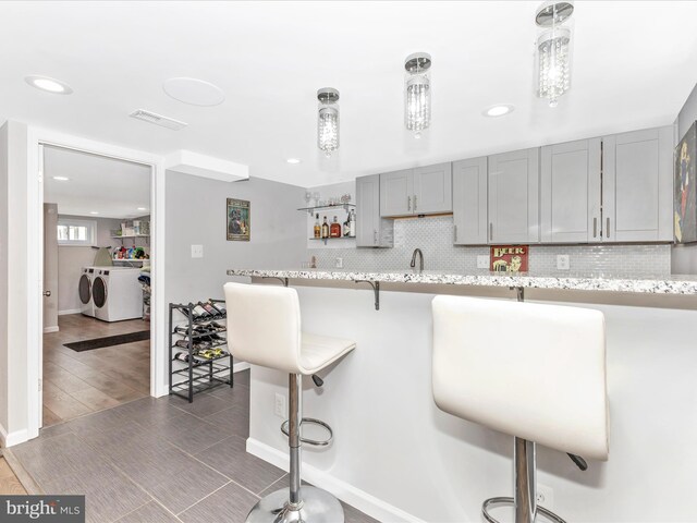 507 Kerwin Ct, Silver Spring, MD 20901 - kitchen with washing machine and dryer, gray cabinets, backsplash, a breakfast bar area, and recessed lighting