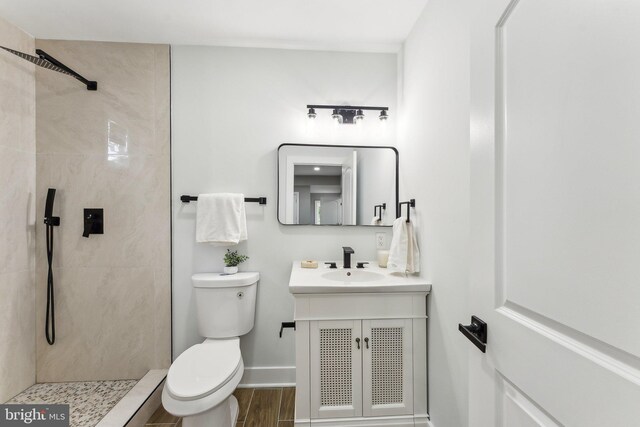 3104 Douglas St NE, Washington, DC 20018 - bathroom featuring toilet, a tile shower, vanity, wood finished floors, and baseboards