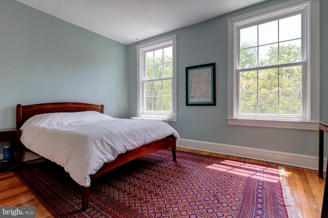 bedroom with baseboards, multiple windows, and wood finished floors
