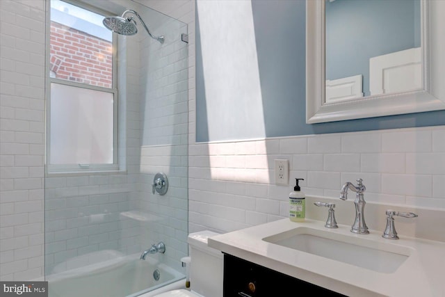 bathroom with tile walls, tasteful backsplash, shower / washtub combination, vanity, and toilet