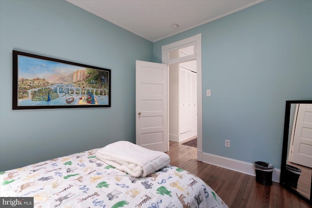 bedroom with baseboards, ornamental molding, and wood finished floors