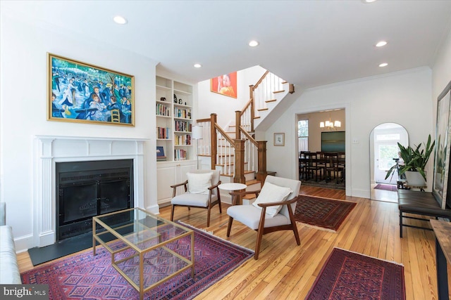 living area featuring a fireplace with flush hearth, hardwood / wood-style flooring, recessed lighting, and stairs