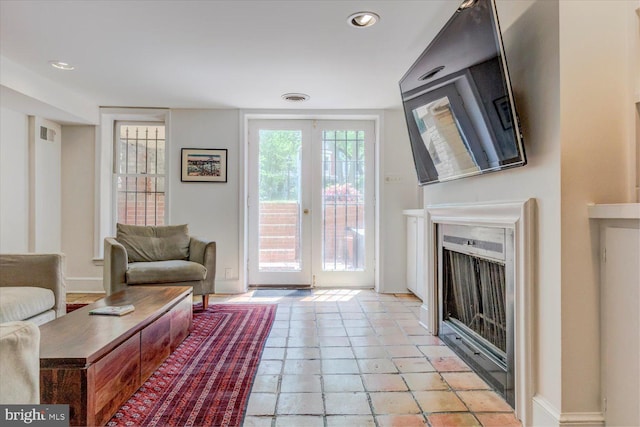 living room featuring baseboards, visible vents, french doors, and a fireplace