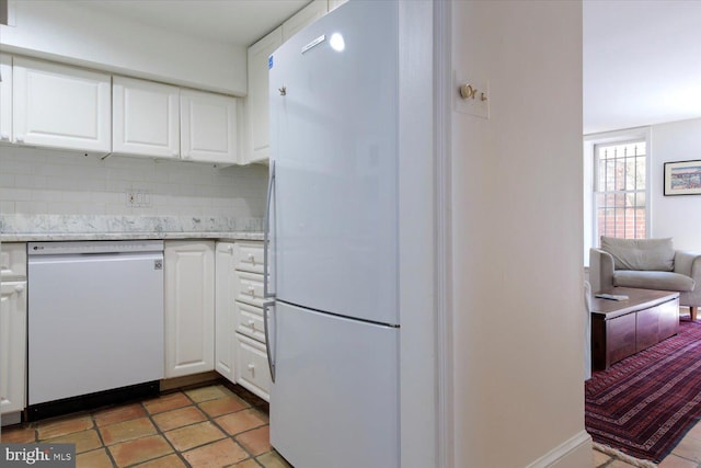 kitchen featuring white appliances, white cabinets, light stone countertops, and tasteful backsplash