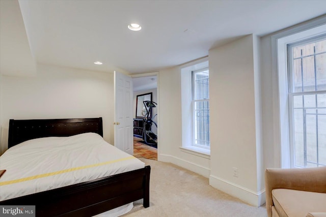 bedroom featuring baseboards, light colored carpet, and multiple windows