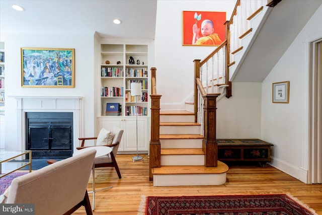 stairway with recessed lighting, baseboards, wood finished floors, and a fireplace
