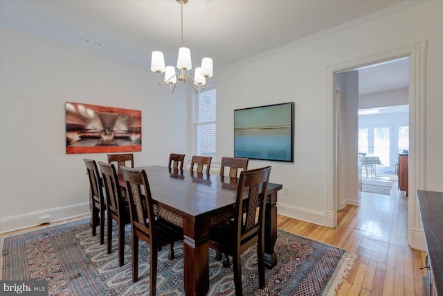 dining space featuring an inviting chandelier, light wood-style flooring, crown molding, and baseboards