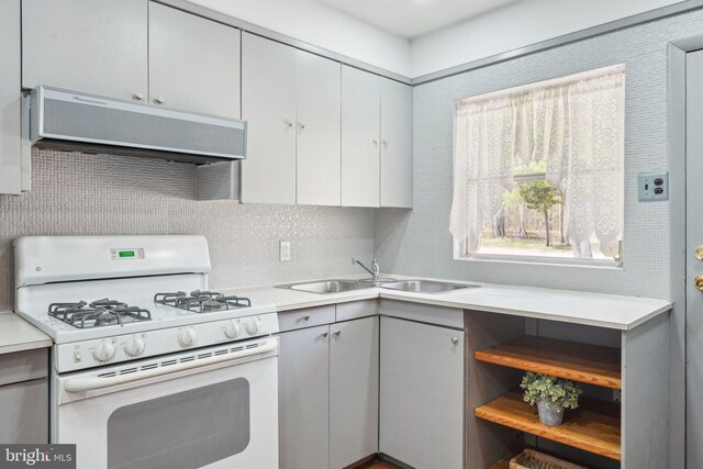 kitchen featuring a sink, light countertops, extractor fan, white gas stove, and decorative backsplash