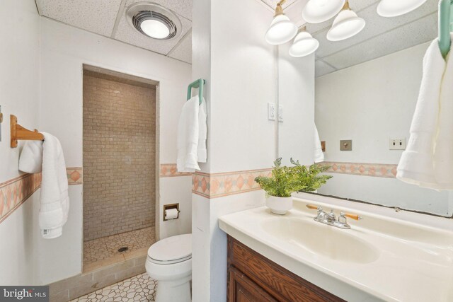 full bathroom with wainscoting, vanity, toilet, a paneled ceiling, and a shower stall
