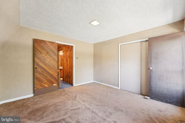 unfurnished bedroom with carpet flooring, a textured ceiling, baseboards, and a closet