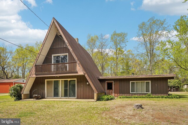 rear view of property featuring a lawn and a balcony