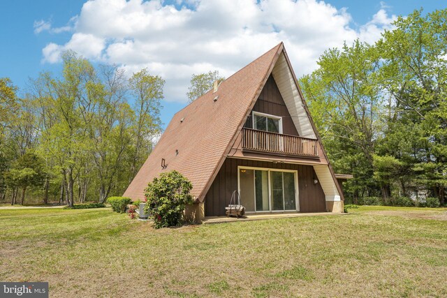 rear view of house with a lawn and a balcony