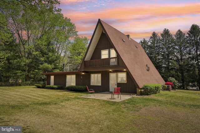 rear view of house with a patio, a yard, and a balcony