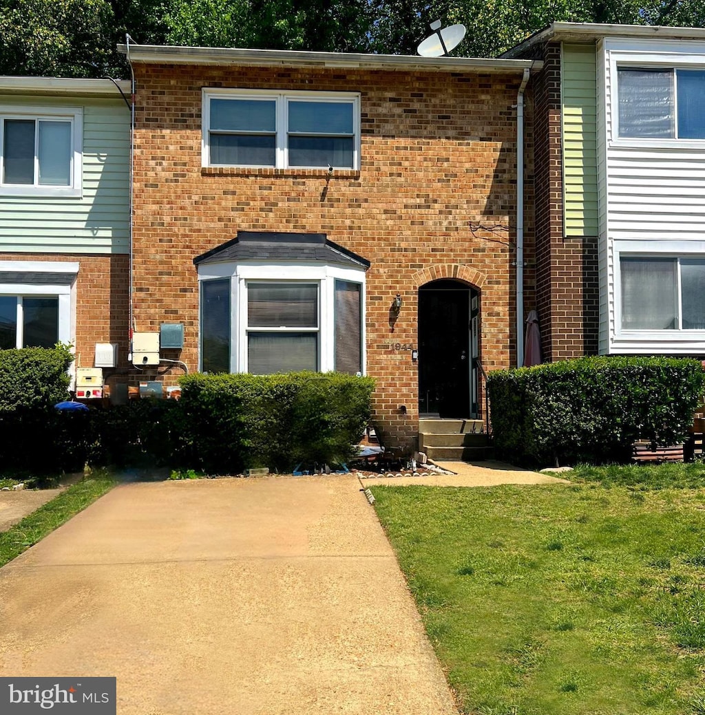 multi unit property featuring a front yard and brick siding