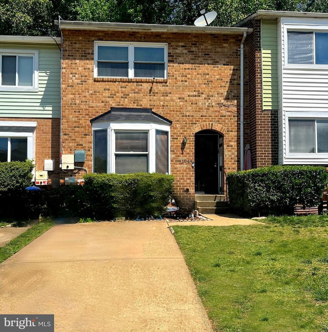multi unit property featuring a front yard and brick siding