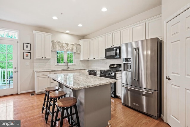 7601 Willow Bottom Rd, Sykesville, MD 21784 - kitchen featuring a breakfast bar, a sink, white cabinetry, black appliances, and backsplash