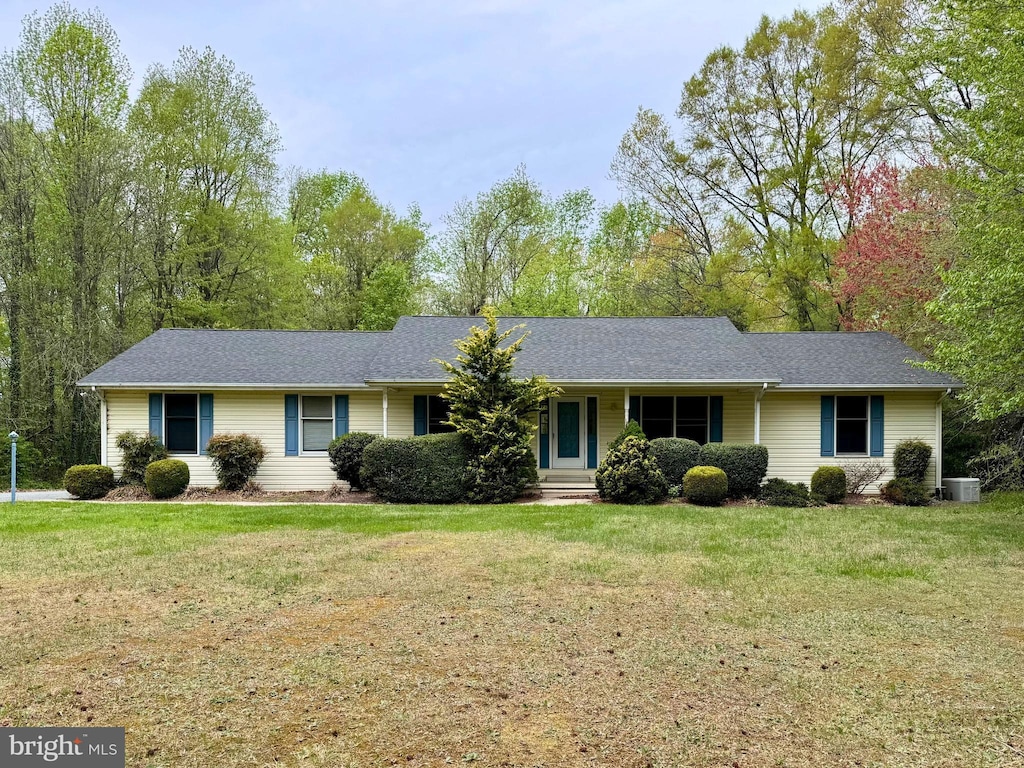 ranch-style house with a shingled roof, a front yard, and central air condition unit