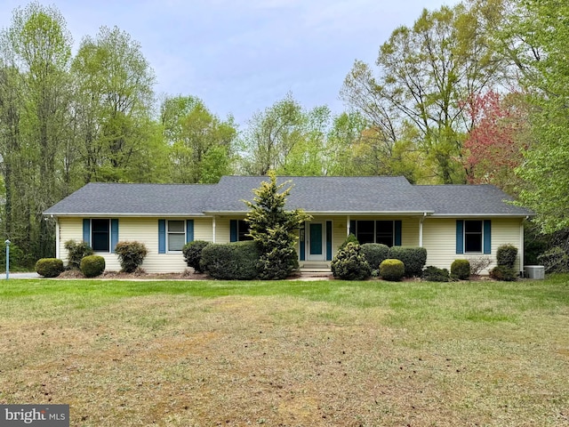 ranch-style house with a shingled roof, a front yard, and central air condition unit