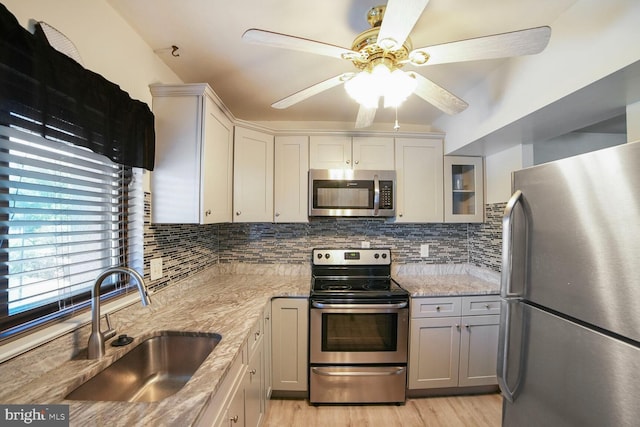 kitchen featuring a sink, ceiling fan, stainless steel appliances, and backsplash