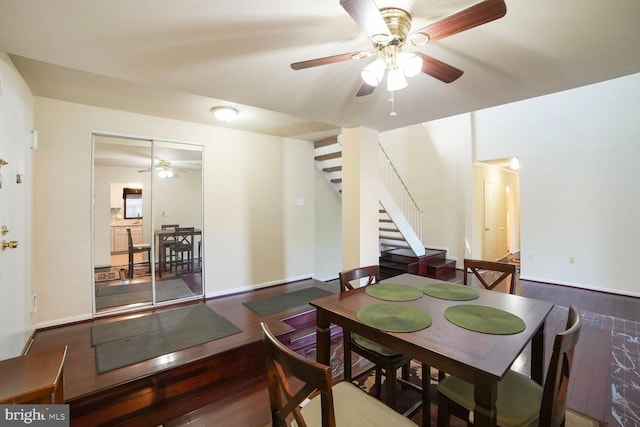 dining area featuring wood finished floors, a ceiling fan, and stairs