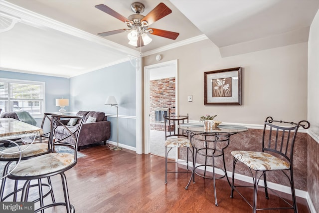 107 Bonnie View Rd, Glen Burnie, MD 21060 - dining area featuring wood finished floors, crown molding, a ceiling fan, a brick fireplace, and baseboards